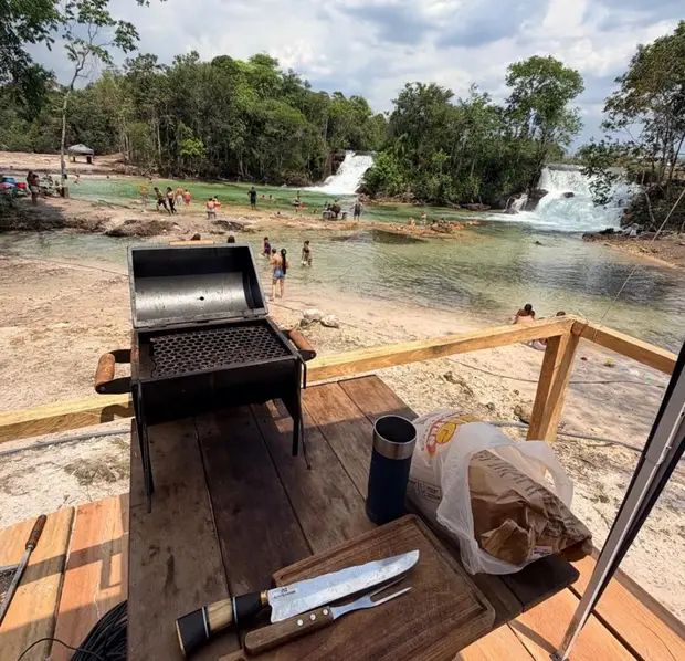 Churrasqueira e tábua de corte numa varanda de quiosque, com vista pras cachoeiras